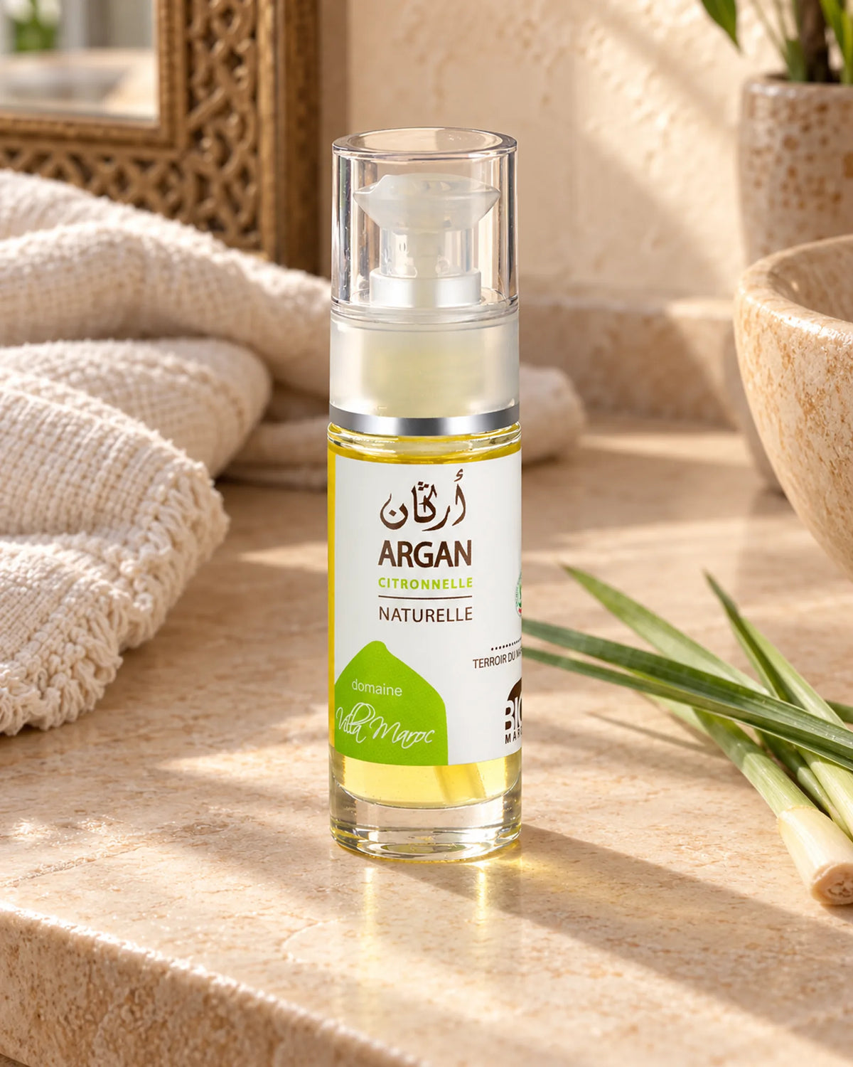Huile d'Argan à la Citronnelle 30ml — vue de trois quarts dans une salle de bain marocaine à la lumière naturelle.