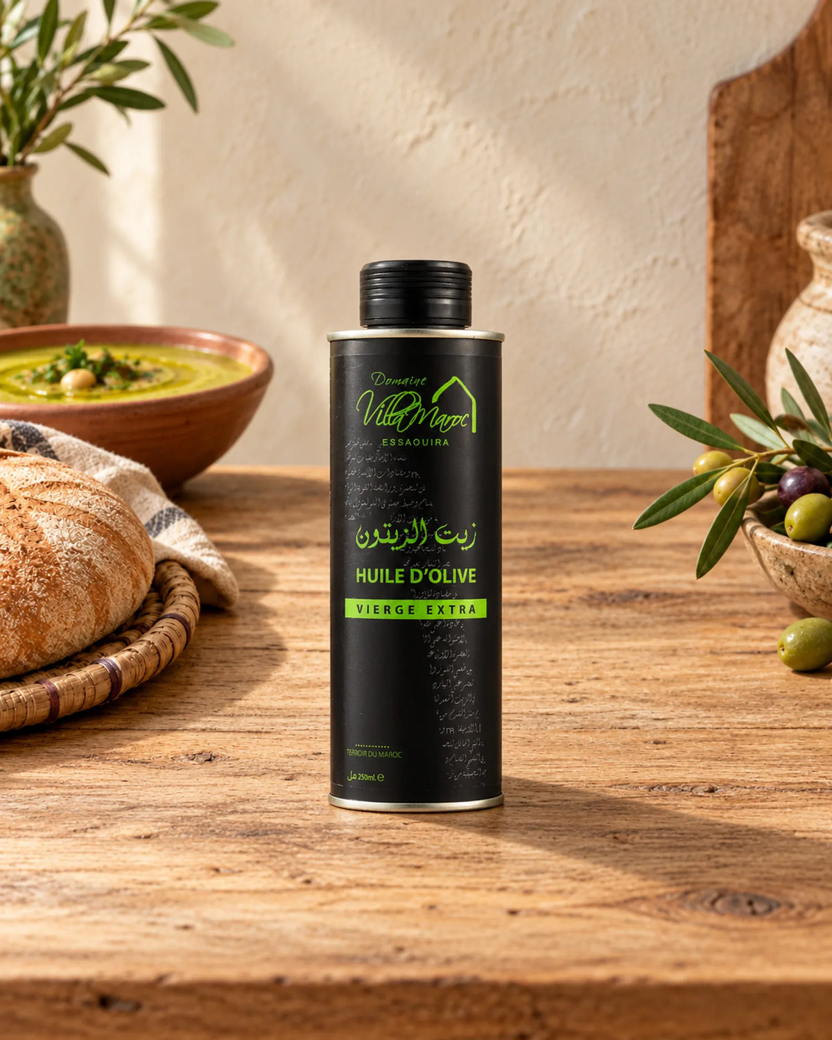 Huile d'Olive Extra Vierge 250ml sur un comptoir en bois, avec du khobz, de la bissara et une branche d’olivier.